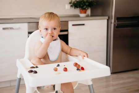 Bebe numa mesa para bebe comendo frutas